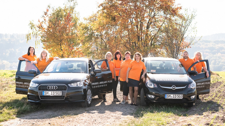 Gruppenbild der Pflegekräfte mit Autos - Immanuel Ambulante Pflege Schmalkalden-Meiningen